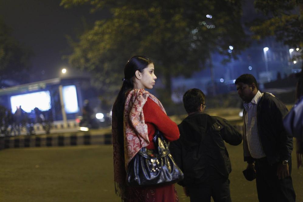 A woman waits at a bus stop in New Delhi